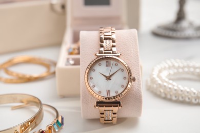 Elegant watch and bijouterie on white marble table