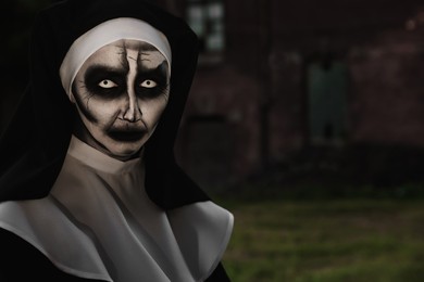 Portrait of scary devilish nun outdoors, space for text. Halloween party look