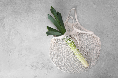 White net bag with leek on light grey table, top view