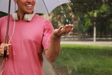 Man with umbrella walking under rain in park, closeup