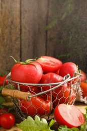 Fresh ripe tomatoes in metal basket on table. Space for text