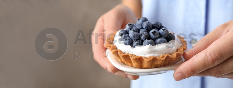 Woman holding plate with blueberry tart, closeup view with space for text. Banner design