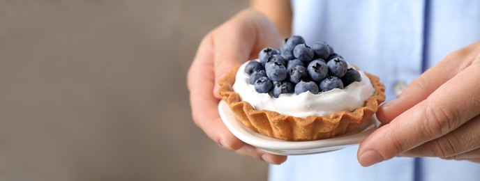 Woman holding plate with blueberry tart, closeup view with space for text. Banner design