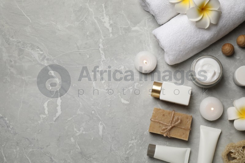 Flat lay composition with towels and skin care products on light grey marble background, space for text