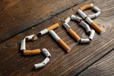 Word Stop of cut cigarettes on wooden table. Quitting smoking concept