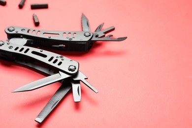 Compact portable black multitool and details on red background, closeup. Space for text