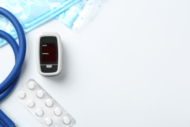 Photo of Flat lay composition with modern fingertip pulse oximeter and medical items on white background. Space for text