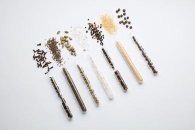 Test tubes with various spices on white background, flat lay
