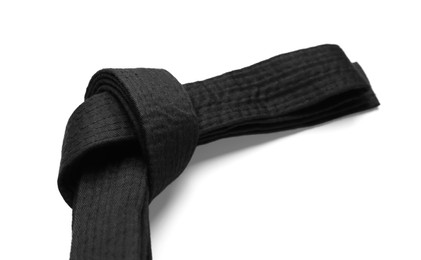 Tied black belt on white background, closeup. Oriental martial arts