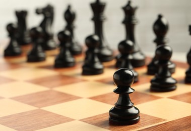 Chessboard with game pieces on light background, closeup. Space for text