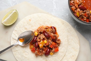 Tasty chili con carne with tortillas on light table, flat lay