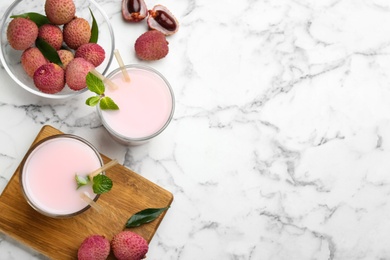 Flat lay composition with delicious lychee cocktail on white marble table. Space for text