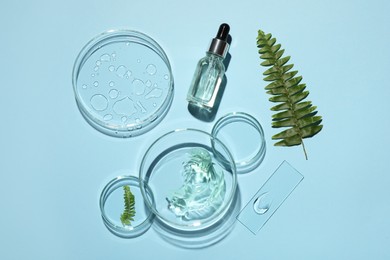 Flat lay composition with cosmetic product, fern and laboratory glassware on light blue background