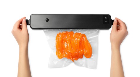Woman using sealer for vacuum packing with plastic bag of bell pepper on white background, top view