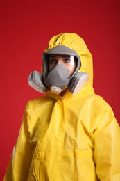 Woman wearing chemical protective suit on red background. Virus research