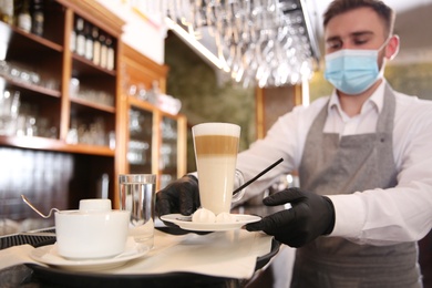 Waiter serving beverages in restaurant. Catering during coronavirus quarantine