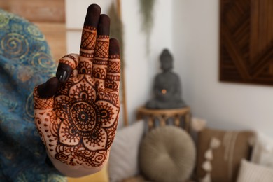 Woman with henna tattoo on palm indoors, closeup and space for text. Traditional mehndi ornament