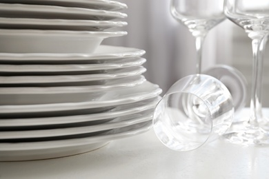 Stacked plates and glasses on white table, closeup