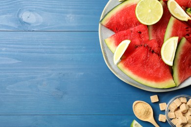 Photo of Cut juicy watermelon served with lime and sugar on blue wooden table, flat lay. Space for text