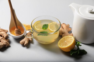 Delicious ginger tea and ingredients on light grey background