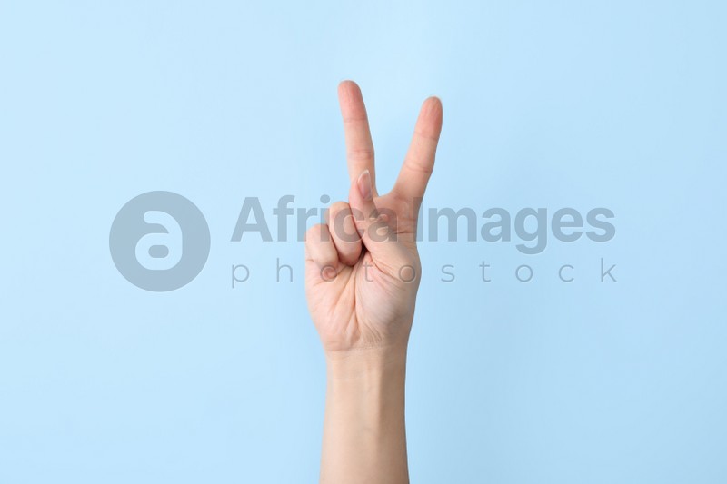 Photo of Woman showing V letter on color background, closeup. Sign language