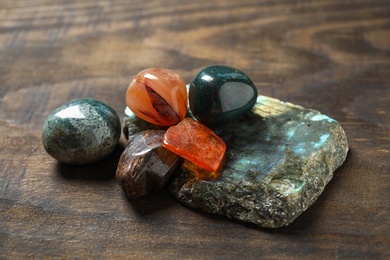 Different beautiful gemstones on textured wooden table