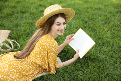 Young woman reading book on green grass