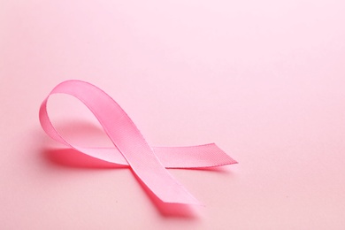 Photo of Pink ribbon on color background, space for text. Breast cancer awareness concept