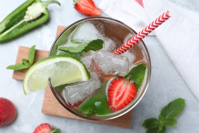 Spicy cocktail with jalapeno, strawberry, lime and mint on light grey table, flat lay