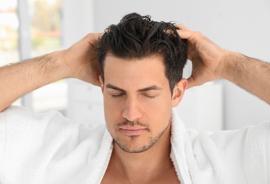 Handsome man applying hair conditioner in bathroom