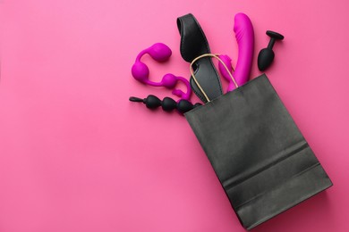 Shopping bag with different sex toys on pink background, flat lay. Space for text