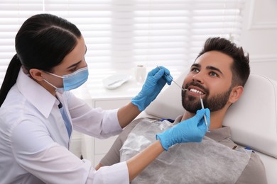 Dentist examining young man's teeth in modern clinic