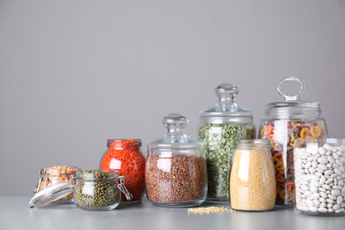 Jars with different cereals on grey table