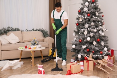 Photo of Man from cleaning service working in messy room after New Year party