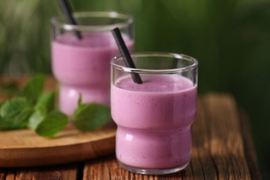 Delicious blackberry smoothie in glasses on wooden table, closeup