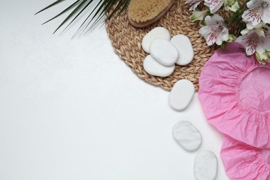 Flat lay composition with shower caps and spa stones on white wooden background. Space for text
