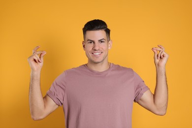 Handsome man snapping fingers on yellow background