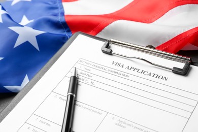 Photo of American flag, visa application form and pen on table, closeup