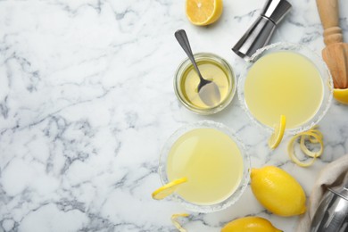 Delicious bee's knees cocktails and ingredients on white marble table, flat lay. Space for text