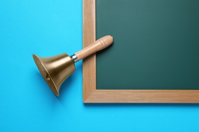 Golden bell and green chalkboard on light blue background, flat lay. School days