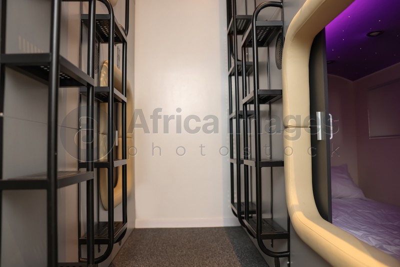 Photo of Capsule and ladders in modern pod hostel. Stylish interior