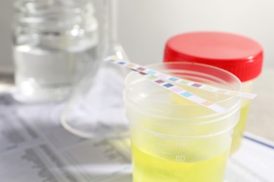 Containers with urine samples for analysis and glassware on test forms, closeup