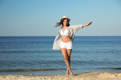 Beautiful young woman in hat on beach