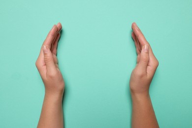 Woman holding on turquoise background, closeup of hands. Space for text