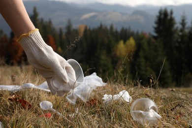 Woman collecting garbage in nature, closeup of hand with crumpled cup. Space for text