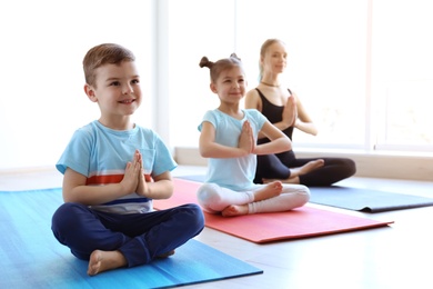 Little children and their teacher practicing yoga in gym