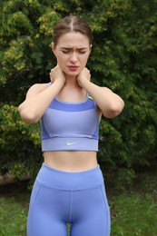 Photo of Young woman suffering from neck pain outdoors
