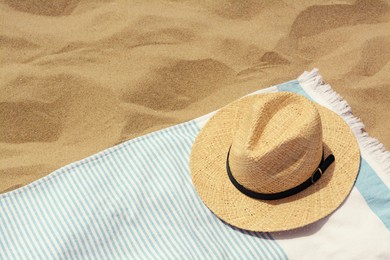 Beach towel with straw hat on sand. Space for text