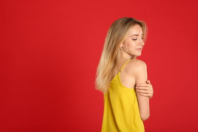 Beautiful young woman with blonde hair on red background. Space for text