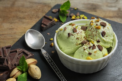 Delicious green ice cream served in ceramic bowl on wooden table
